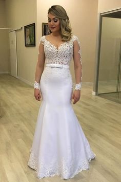 a woman in a white wedding dress posing for the camera with her hands on her hips