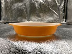 an orange bowl sitting on top of a shiny surface