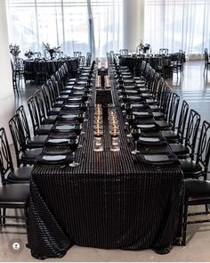 a long table is set up with black chairs and place settings for an elegant dinner