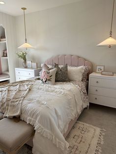 a bedroom with a large bed and two lamps on the ceiling above it is decorated in white