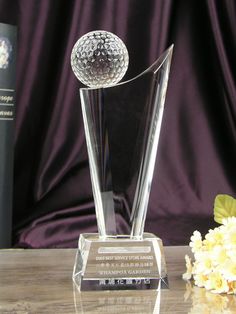 a crystal trophy with a golf ball on top