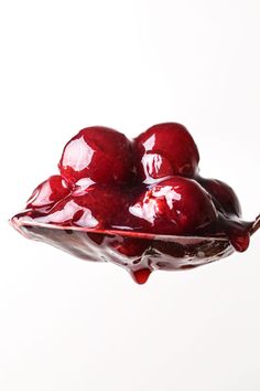 a glass bowl filled with cherries on top of a table