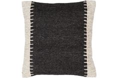 a black and white pillow with fringes on the front, sitting against a white background