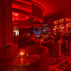 a dimly lit room with red lighting and people sitting at tables in the background,