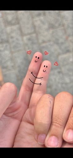 two fingers with faces drawn on them and hearts in the middle, one is smiling