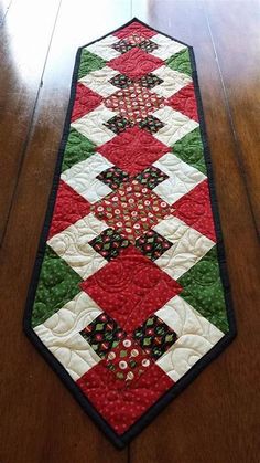 a red and green table runner on a wooden floor with a black border around it