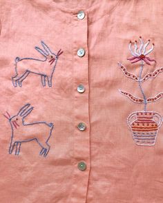 a pink shirt with embroidered animals on it