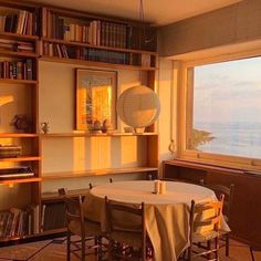 a dining room with a table and bookshelves in front of a large window