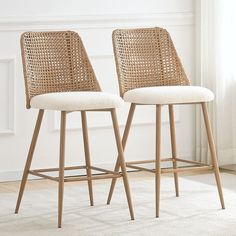 two wicker barstools in front of a window with white walls and carpet