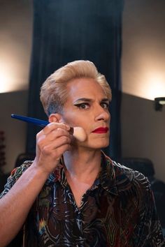 a woman holding a pencil in front of her face and looking at the mirror behind her