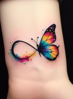 a colorful butterfly tattoo on the side of a woman's foot with watercolor paint