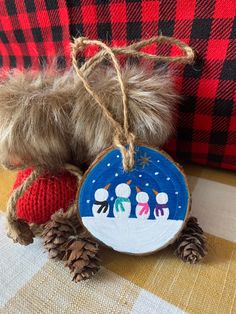 a wooden ornament with snowmen on it sitting next to a plaid couch