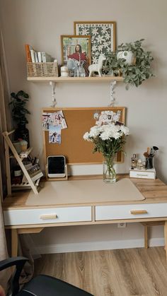 a desk with flowers and pictures on the wall