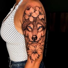 a woman's arm with a wolf and flowers tattoo on her left shoulder, which is covered in mesh