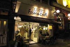 people are sitting at tables in front of a fish and chip restaurant