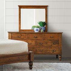 a bedroom scene with focus on the dresser and mirror, which has a plant on top