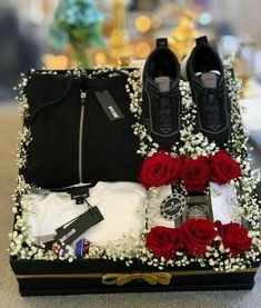 an open suitcase with shoes, t - shirts and flowers in it sitting on a table