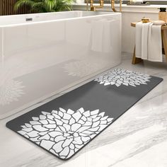 a bath tub sitting next to a white and black rug on the floor in a bathroom