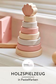 a pink and white wooden stacking toy with text overlay that reads, holspieezug in pastelfarben