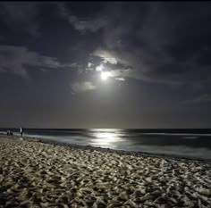 people walking on the beach at night near the ocean