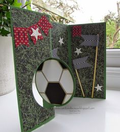 an open card with a soccer ball and stars on it, sitting next to a potted plant