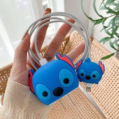 a hand holding a blue phone charger with two little monsters on it's sides