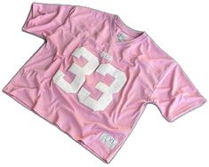 a pink shirt with white numbers on the front and back, sitting on a white surface