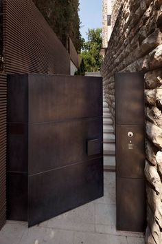 two metal doors are open on the side of a stone building with stairs leading up to it