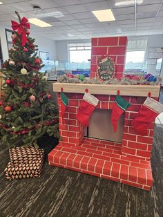 an office decorated for christmas with stockings and stocking on the fire place next to a tree