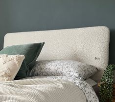 a bed with two pillows on top of it next to a night stand and potted plant