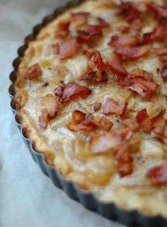 a bacon and cheese quiche sitting on top of a paper towel in a pie pan