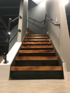 a set of wooden stairs leading up to the top floor in a building with white walls and metal railings