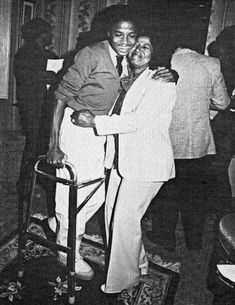 an old black and white photo of two people hugging each other in a living room