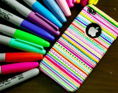 an iphone case with many pens and markers on it, sitting next to a pile of pens