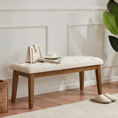 a white bench sitting on top of a wooden floor next to a potted plant