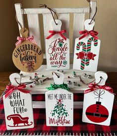 wooden tags with christmas designs on them are displayed in front of a red and white checkered tablecloth