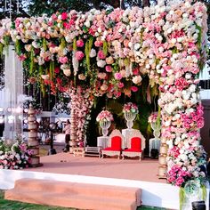 a decorated stage with flowers and chairs for an outdoor wedding ceremony in the evening hours