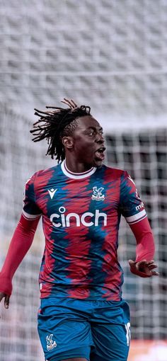 a soccer player with dreadlocks on his head is in the middle of a play