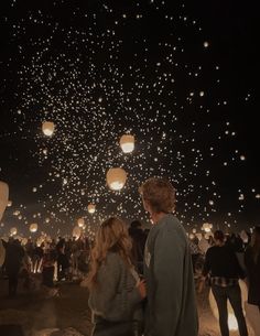 two people looking at the sky full of lanterns