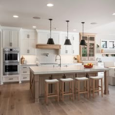 a large kitchen with white cabinets and wooden flooring, along with an island in the middle