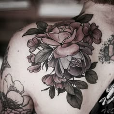 a woman's back with flowers on it, and tattoos on her upper arm