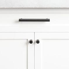 a black handle on a white cabinet door