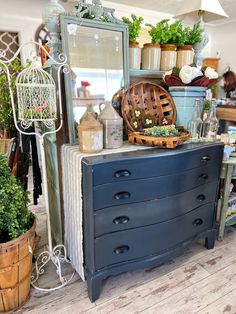 an old dresser with lots of potted plants on top and a mirror above it