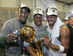 three basketball players pose for a photo with the trophy