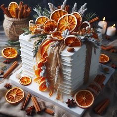 an orange decorated cake with cinnamons and spices around it on a table next to candles