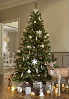 a christmas tree with presents under it and a deer figurine next to it