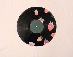 a black record with strawberrys on it sitting on a white tableclothed surface