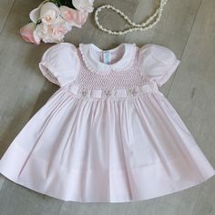 This Sweet Little Smocked Dress Is Precious! So Many Details!!! The Dress Is Done In A Cotton Blend In A Pale Pink Hue. The Bodice Is Fully Smocked In A Honeycomb Design. The Smocking Is Bordered By More Smocking That Is Done In An Accordion Style. A Matching Pink Belt Weaves Through The Smocking. In Between The Woven Belt Are Hand Embroidered Floral Bouquets Done In Pink, Lavender And Dusty Rose. Yellow And White Bullion Rosebuds Surround The Embroidered Roses. The Short Puff Sleeves Have A Mat Heirloom Embroidery, Smocking Tutorial, Hand Smocked Dress, Smocking Plates, Smocked Baby Dresses, Pink Belt, Vintage Baby Clothes, Embroidered Roses, Honeycomb Design