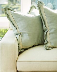 two pillows sitting on top of a couch next to each other in front of a window