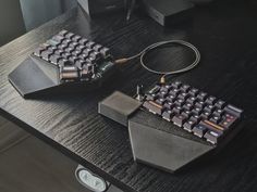 two computer keyboards sitting on top of a wooden table next to a mouse and cable